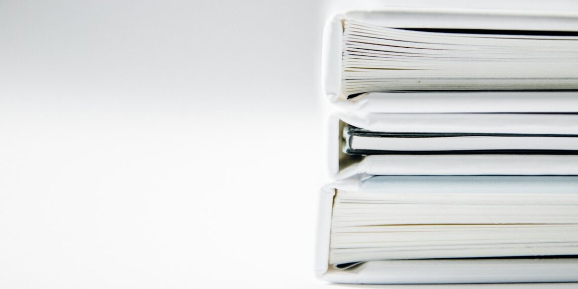 Expedientes técnicos archivados y apilados sobre un fondo claro